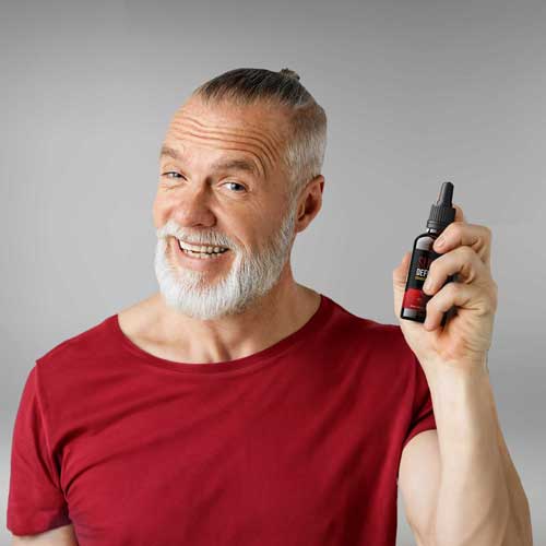 Male in red shirt holding Sugar Defender bottle.